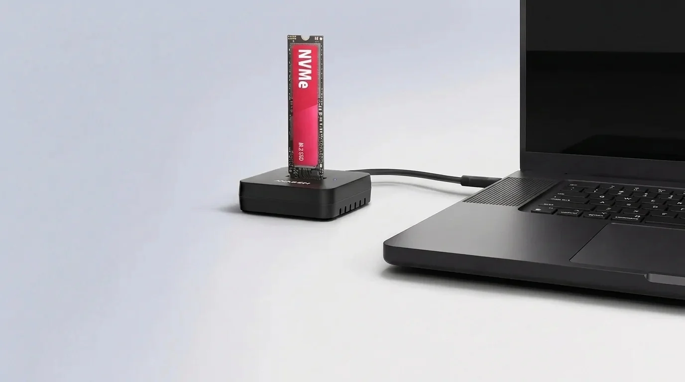 Dokovacia stanica AXAGON ADSA-M2C11L so zasunutým M.2 NVMe SSD diskom prepojená káblom s notebookom.