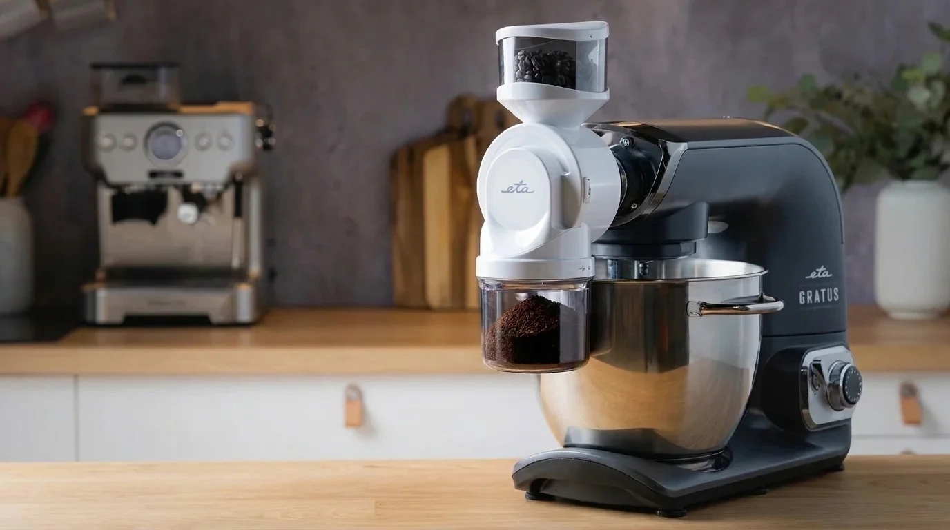 Bílý kávomlýnek ETA připevněný k šedému kuchyňskému robotu ETA Gratus s kávovými zrny v horní násypce a mletou kávou v dolní nádobce.