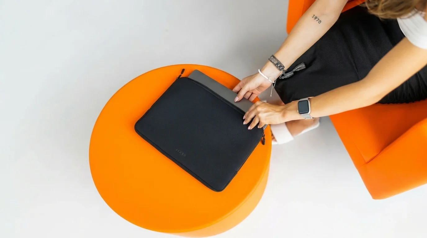 Vkládání tabletu do černého pouzdra Fixed Sleeve na kulatém oranžovém stolku.