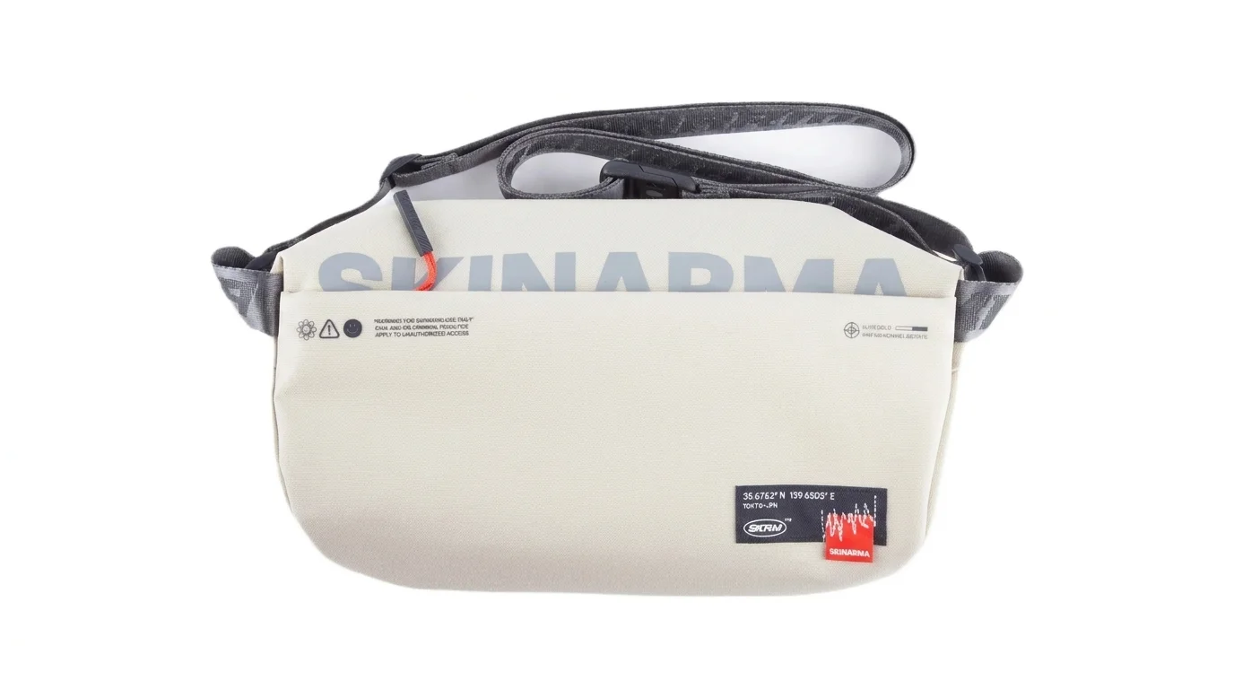 Béžová crossbody taška Skinarma Fardel s nápisem značky a nastavitelným ramenním popruhem.