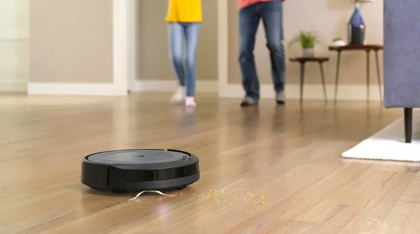 Robotický vysavač iRobot Roomba na dřevěné podlaze uklízí rozsypané drobky.