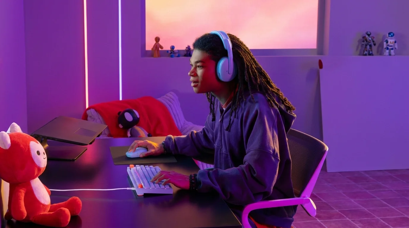 Hráč se sluchátky sedí u stolu s klávesnicí a ovládá fialovou herní myš Logitech G305 X SUPERLIGHT.