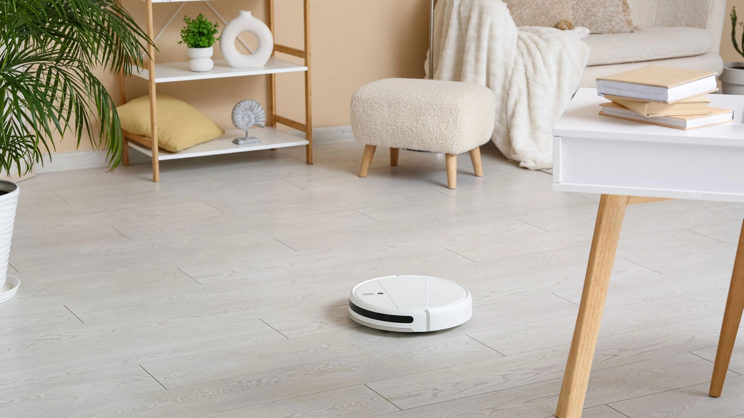 Bílý robotický vysavač Sencor na světlé podlaze v moderně zařízeném obývacím pokoji.