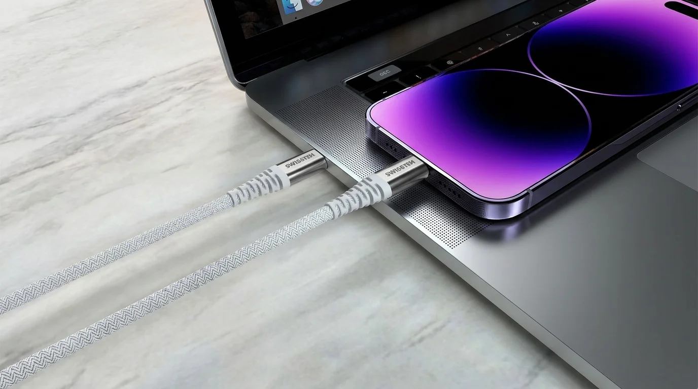 Bílý textilně opletený kabel Swissten zapojený do notebooku a smartphonu.