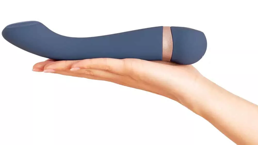 Tmavomodrý vibrátor Hot & Cold PlusOne DEI 6729 s medeným krúžkom položený na otvorenej dlani.
