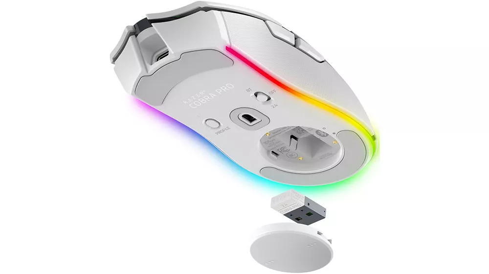 Spodná strana bielej bezdrôtovej myši Razer Cobra Pro s RGB podsvietením a vybratým USB prijímačom s okrúhlym krytom.