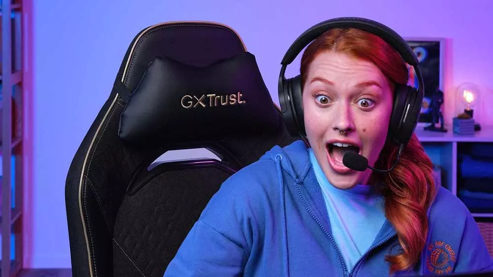 Nadšená hráčka so slúchadlami s mikrofónom sedí v čiernej hernej stoličke Trust GXT.