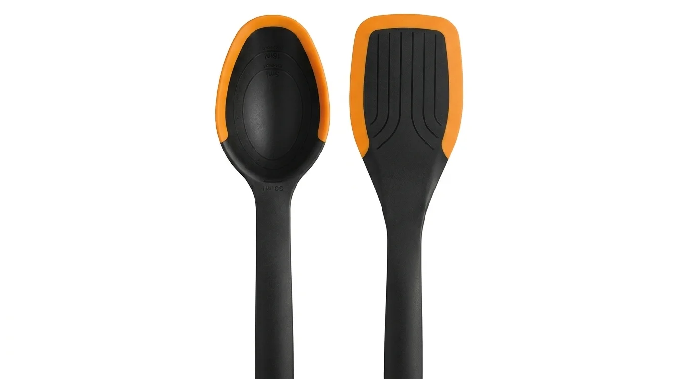 Černá servírovací lžíce s odměrkou a obracecí lopatka Fiskars s oranžovými silikonovými okraji.
