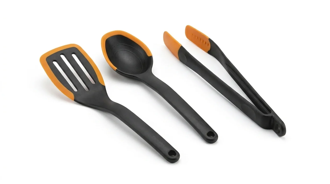 Černá kuchyňská obracečka, lžíce a kleště Fiskars Functional Form s oranžovými silikonovými okraji.